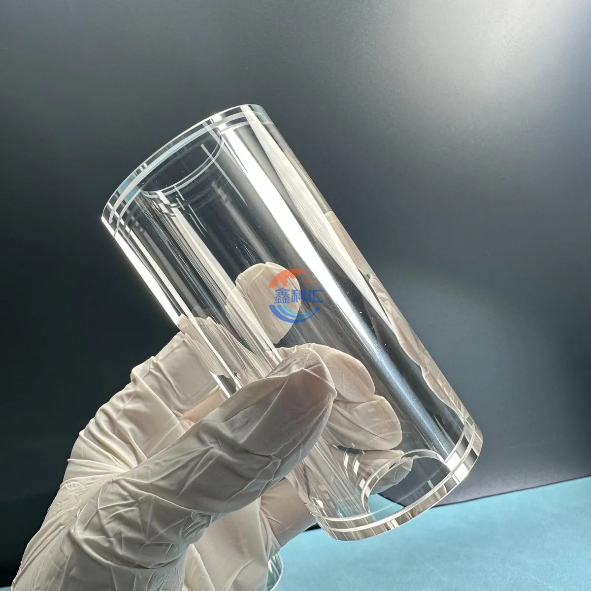 Gloved hand holding a transparent sapphire tube during visual inspection